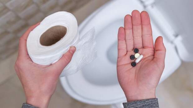 Man holding laxatives next to toilet