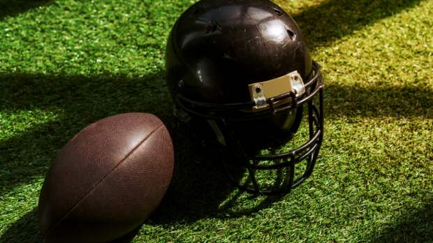 A football sits by a helmet.