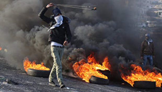 Протестующие во время столкновений на границе Палестины и Израиля в районе Рамаллы. 11 декабря 2017