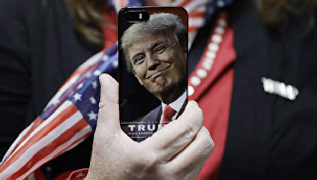 Женщина держит телефон с фотографией Дональда Трампа во время предвыборной кампании в США Женщина держит телефон с фотографией Дональда Трампа во время предвыборной кампании в США