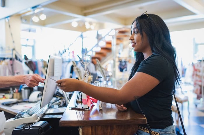 A young adult pays for a shopping purchase with a credit card.