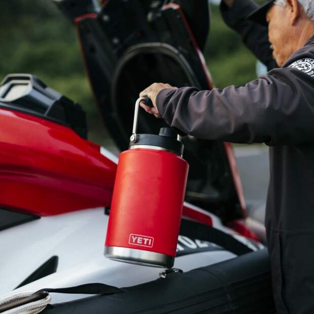 Hawaiian lifeguard holding a stainless steel YETI half-gallon jug in rescue red colors