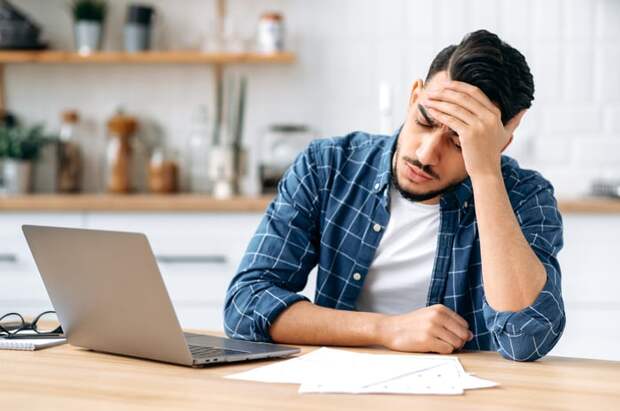 A person at a laptop holding their head.