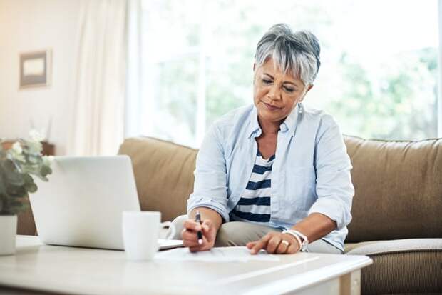 A person at a table with a laptop holding a pen.