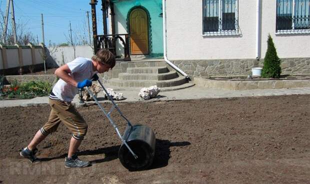 Процесс прикатки почвы для газона специальным катком