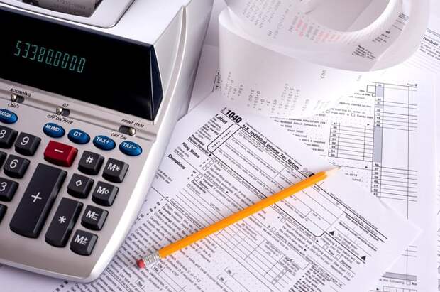 An adding machine sitting on top of tax forms.