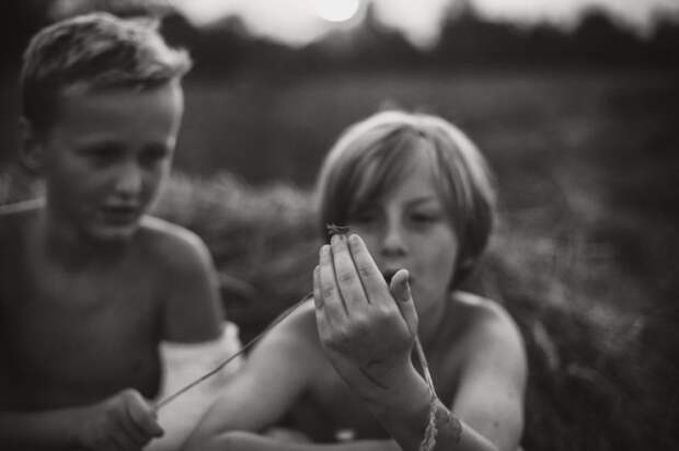 dos niños mirando la mano de uno de ellos con un grillo en su dedo 