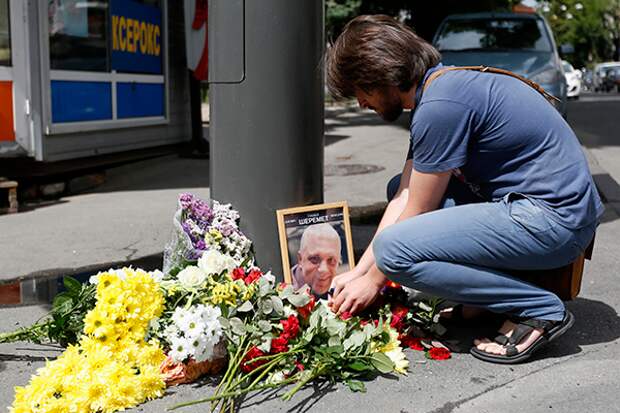 A man lights a candle by a portrait of Pavel Sheremet surrounded with flowers and candles at a place of his death in Kiev, Ukraine, Wednesday, July 20, 2016. A prominent journalist was killed in a car bombing in Ukraine's capital, Kiev, on Wednesday, sending shockwaves through the Ukrainian journalist community that was shaped by the gruesome killing of the publication's founder 16 years ago. (AP Photo/Sergei Chusavkov)