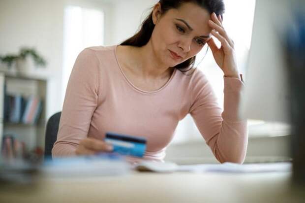 A woman with a credit card, looking worried.