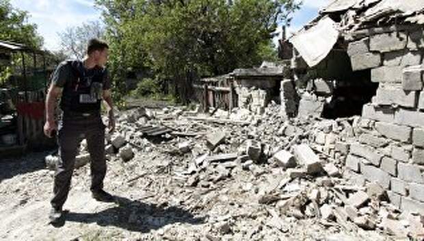 Сотрудник ОБСЕ осматривает двор жилого дома, пострадавший в результате обстрела Докучаевска в Донецкой области. Архивное фото