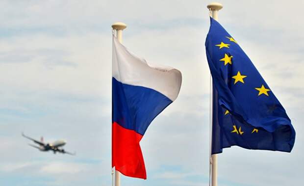 Флаги России, ЕС и Франции на набережной Ниццы. На дальнем плане - самолет заходит на посадку в международный аэропорт Ниццы.