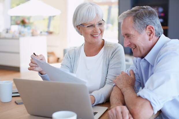 Two smiling people at a laptop.