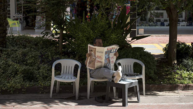 Мужчина читает газету на улице курорта Кемер в Турции. Архивное ыото