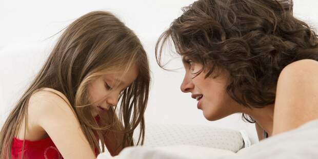 Mother and daughter talking on bed