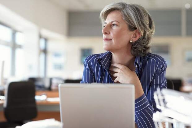 A person staring into the distance while sitting in front of a laptop.
