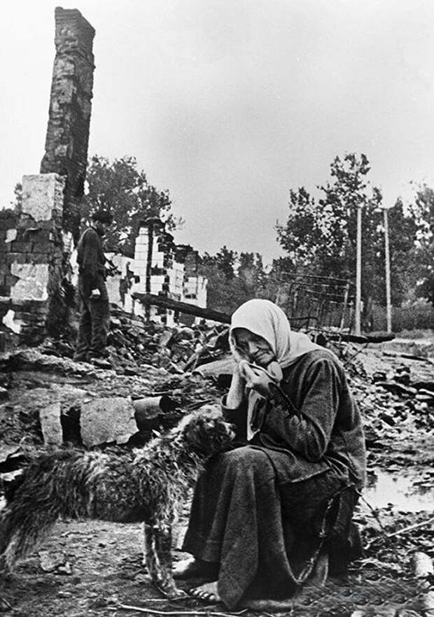 Женщина сидит на пепелище родного дома, разрушенного немцами.
