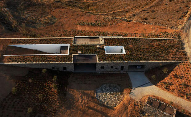 Частный дом на греческом острове Антипароса построен на стыке двух склонов. Длинные каменные стены позволяют ему естественным образом вписаться в окружающее пространство. 