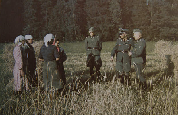 Новинки, 15 августа 1941 г. Г. Гиммлер (второй справа), его адъютант Вернер Гротманн (третий справа) и неизвестный (возможно, переводчик) беседуют с работницами совхоза.