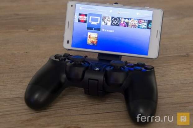 Джойстик и смартфон с запущенным меню PS4