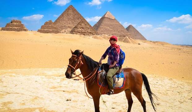 Woman nomad riding a camel at the Pyramids in Egypt