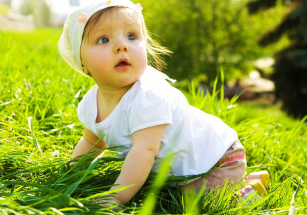 Summer portrait of beautiful baby girl on the lawn