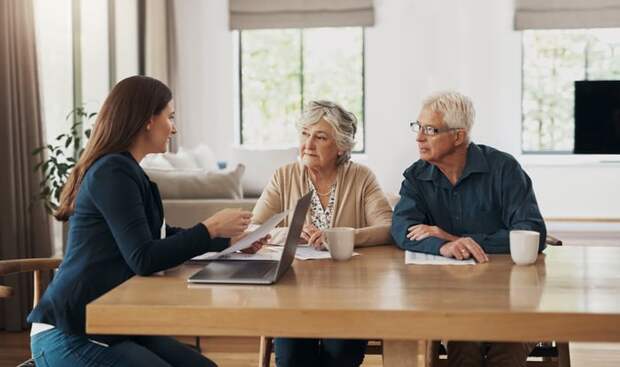 Three people discussing paperwork at a table.