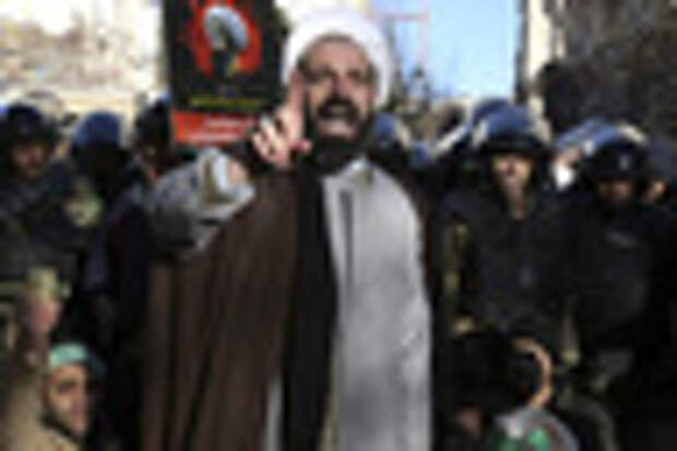 Surrounded by policemen, a Muslim cleric addresses a crowd during a demonstration to protest the execution of Saudi Shiite Sheikh Nimr al-Nimr, shown in the poster in background, in front of the Saudi embassy in Tehran, Iran, Sunday, Jan. 3, 2016