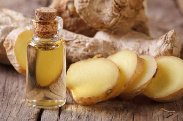 ginger oil in a glass bottle close-up, against the background of the root. horizontal