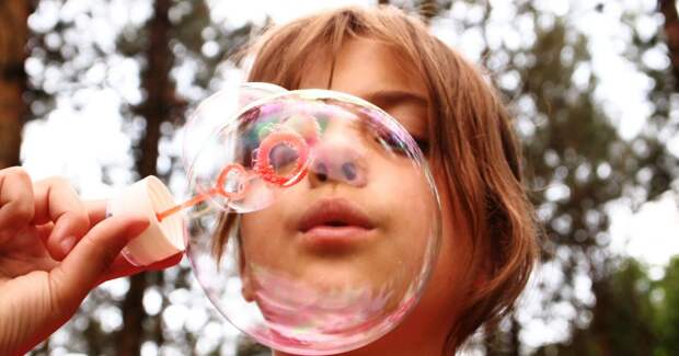Ребёнок надувает мыльные пузыри