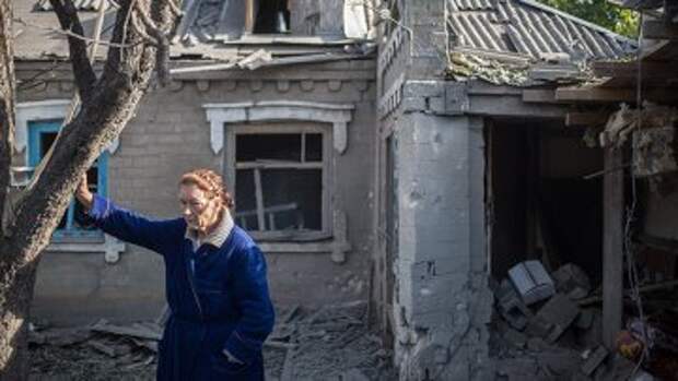 Женщина у поврежденного в результате обстрела дома в поселке Александровка. Архивное фото