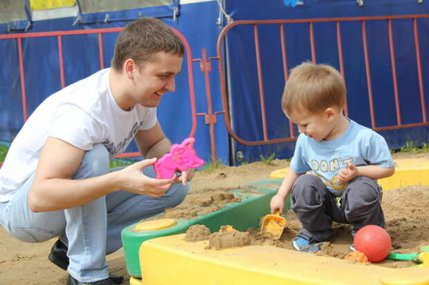 Отец с малышом играют в песочнице