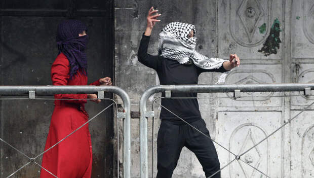 Молодая женщина из Палестины бросает камни в сторону израильских сил безопасности во время столкновений