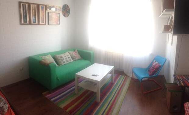 Светлая квартира-студия, яркий зеленый диван в гостиной