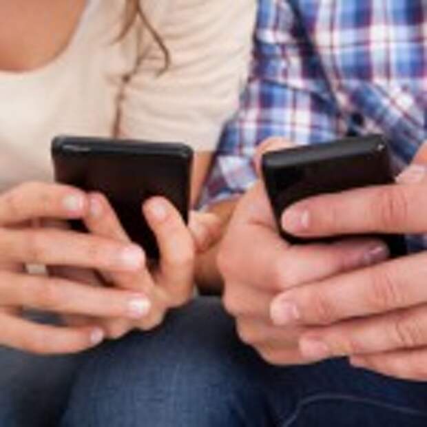 Portrait Of A Happy Couple Sitting On Couch Using Cellphone