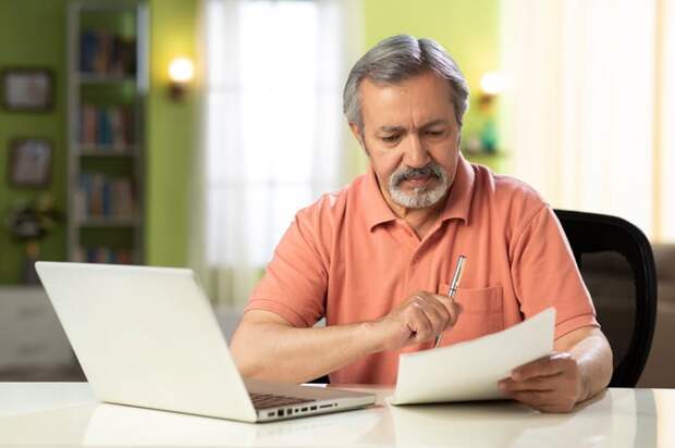 Person sitting in front of laptop looking at document.