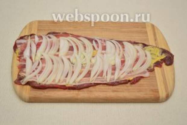 На бекон выложить нарезанный репчатый лук.