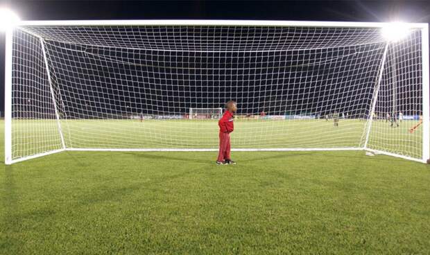 мальчик стоит на воротах на стадионе, фото
