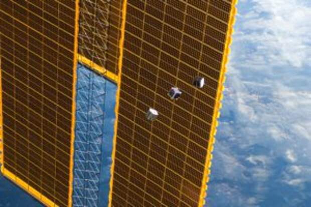 Three tiny CubeSats drift alongside the ISS solar arrays. (Image Credit: NASA)