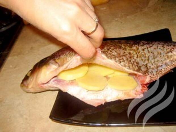 2. Рыбу почистить срезать плавники, выпотрошить.<br>3. Картофель нарезать тонкими кружками. Выложить внутрь рыбы.