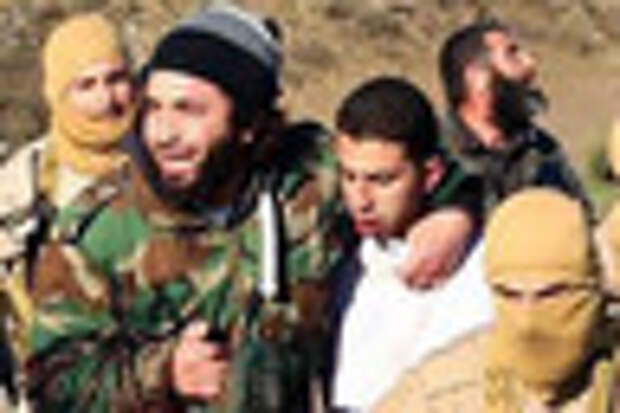 FILE - This Wednesday, Dec. 24, 2014 file image posted by the Raqqa Media Center, which monitors events in territory controlled by Islamic State militants with the permission of the extremist group, shows militants with a captured pilot, Mu'ath Al-Kaseasbeh, wearing a white shirt, in Raqqa, Syria.  A video released online Tuesday, Feb. 3, 2015, purportedly shows a Jordanian pilot captured by the Islamic State extremist group in Syria last month being burned to death by his captors. The Associated Press was not immediately able to confirm the authenticity of the video, which was released on militant websites and bore the logo of the extremist group's al-Furqan media service