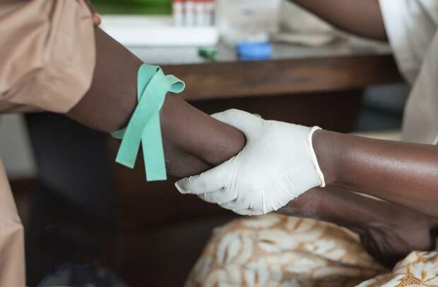 Африканский доктор держит за руку больного