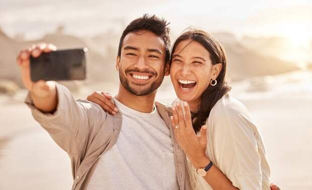 Couple smiling and taking selfie with engagement ring