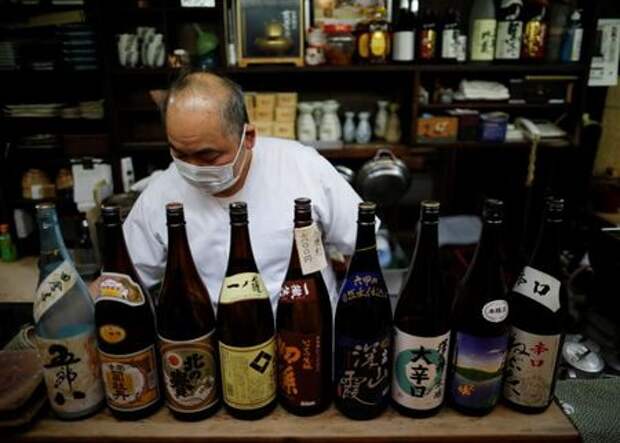 The chef of an izakaya, a Japanese-style dining bar, prepares to close around 20:00 local time next to sake bottles, amid the coronavirus disease (COVID-19) outbreak, in Tokyo, Japan February 2, 2021. REUTERS/Issei Kato
