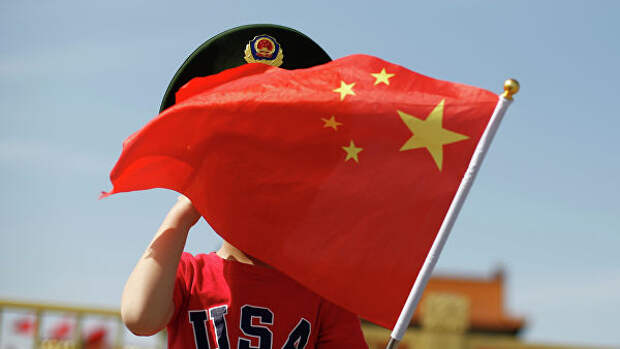 Мальчик в футболке с надписью США машет национальным флагом Китая на площади Тяньаньмэнь в Пекине