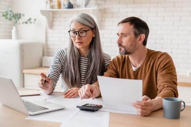 Two people looking at documents and a laptop.
