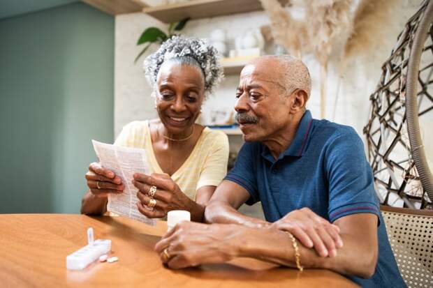 Couple sitting at dining room table looking at document.