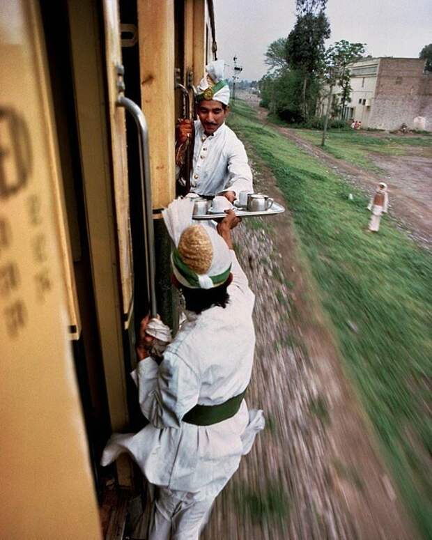 Официанты передают друг другу утренний чай между вагонами на железной дороге в Пакистане, 1983 год знаменитости, исторические фотографии, история, редкие фотографии, фото