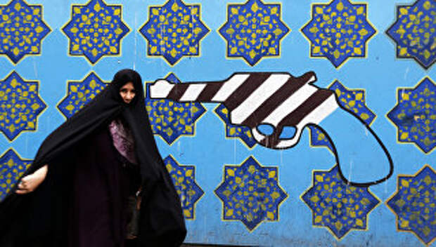 Иранская женщина проходит мимо граффити на стене бывшего посольства США в Тегеране