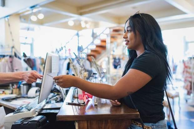 Young woman paying cashier with credit card in a clothing store