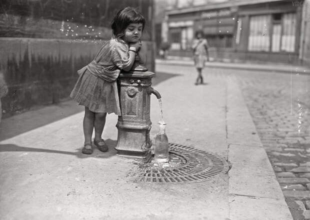 Девочка набирает воду из уличного крана. Франция, Париж, 1921 год.